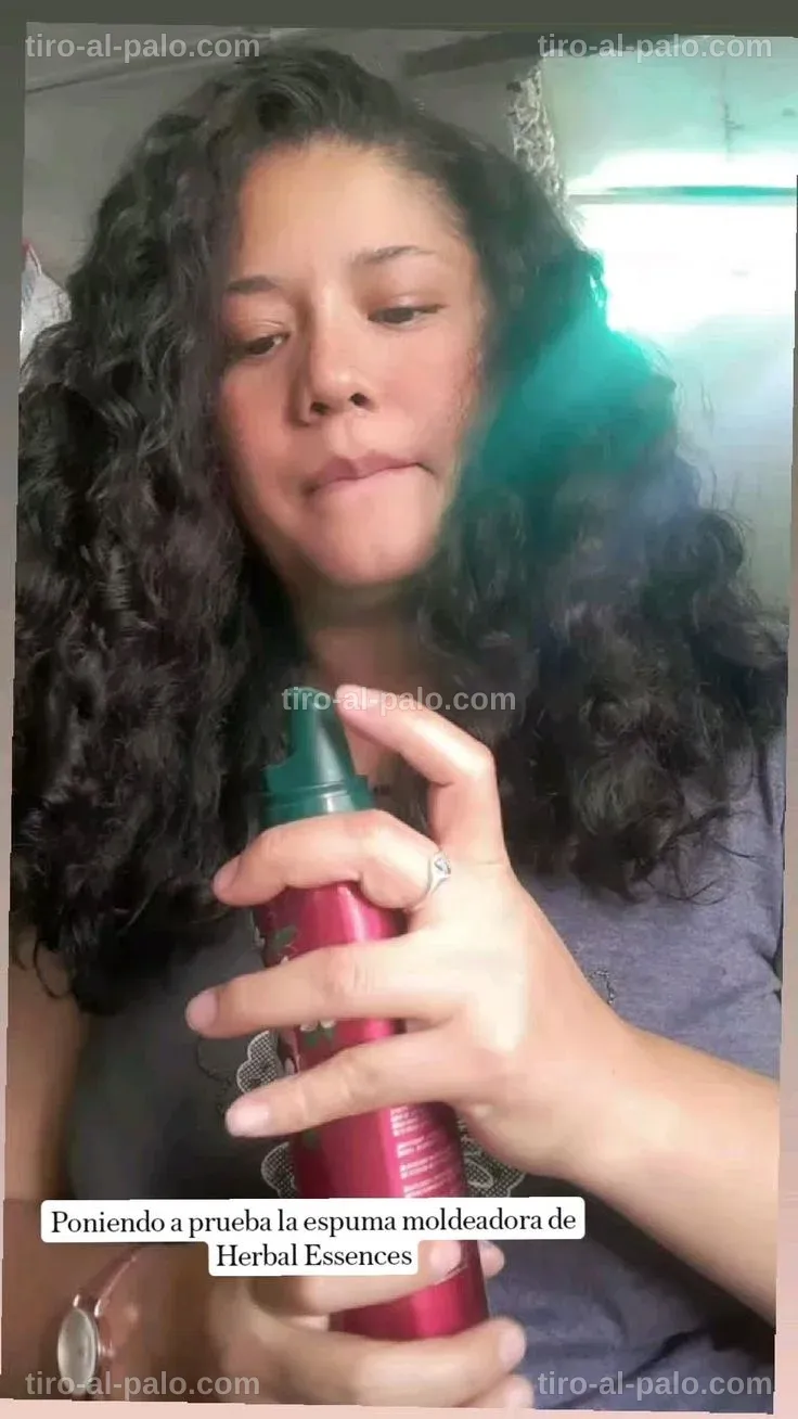 Manos aplicando espuma en rizos para definir la textura del cabello.