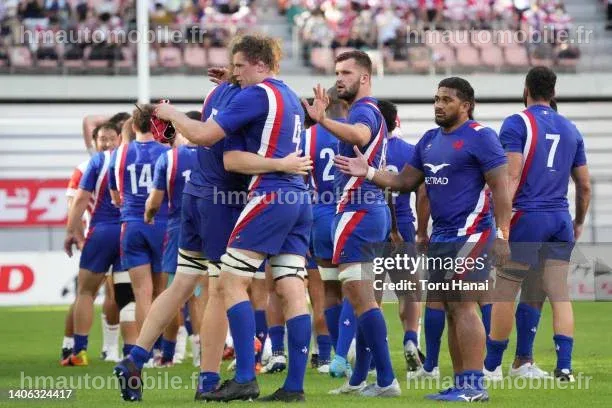 Joueurs français célébrant une victoire contre le Japon lors d'un match de rugby.