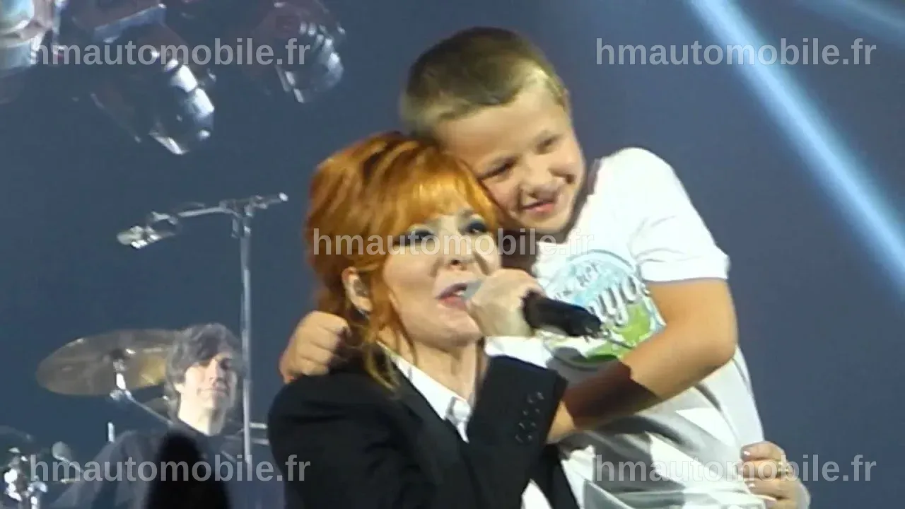 Mylène Farmer entourée d'enfants, partageant un moment de joie.
